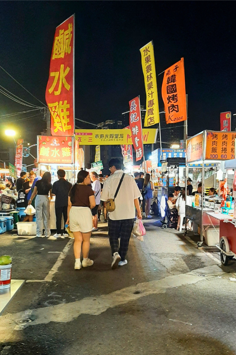 Red and yellow flags waving with people at Wusheng Night Market